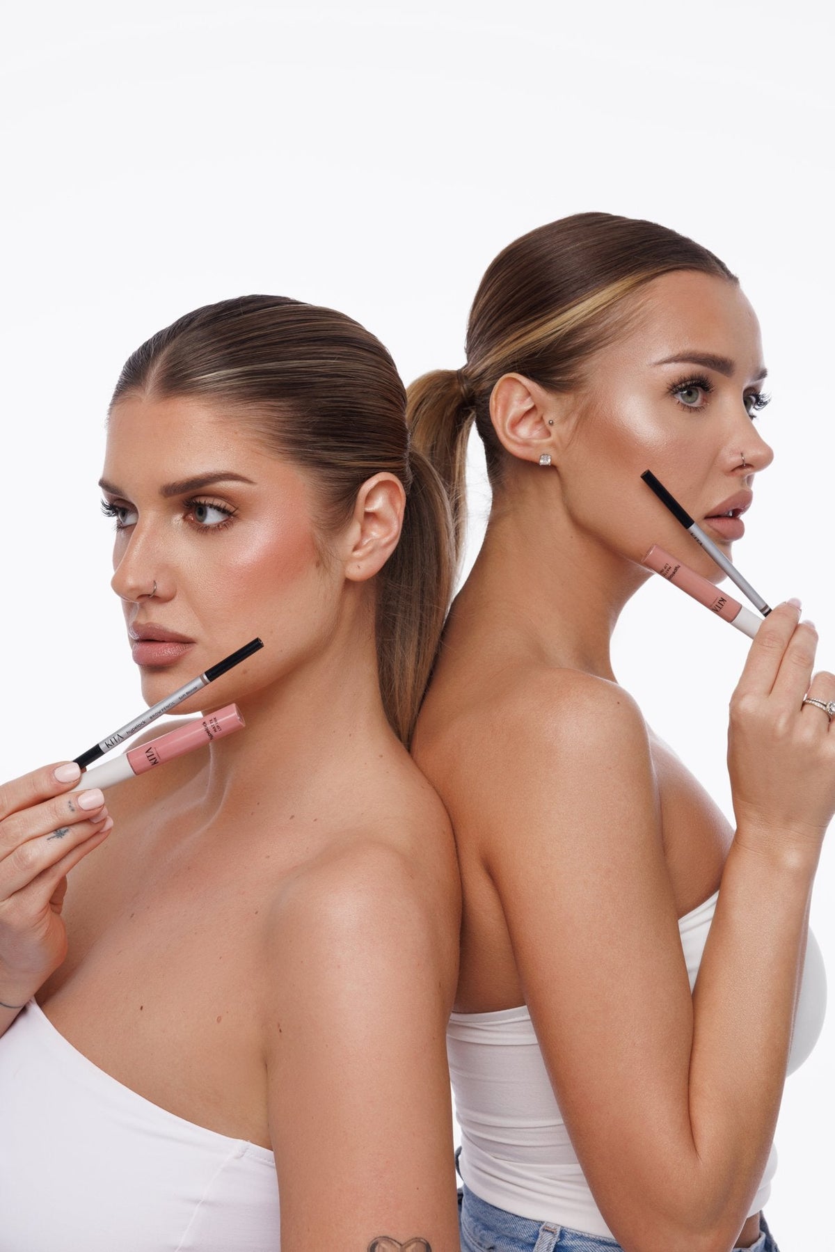Dwie modelki KITA Cosmetics tyłem do siebie z konturówkami i pomadkami